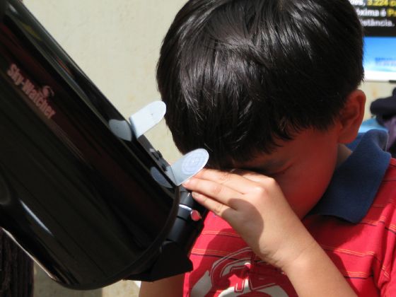 Criança observa o Sol ao telescópio