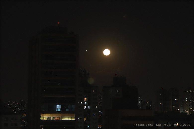 Conjunção de 5 de julho de 2020 vista de São Paulo, com a Lua ainda baixa no horizonte. Júpiter pode ser visto à esquerda da Lua. Saturno está muito abaixo, escondido pelos prédios próximos ao horizonte.