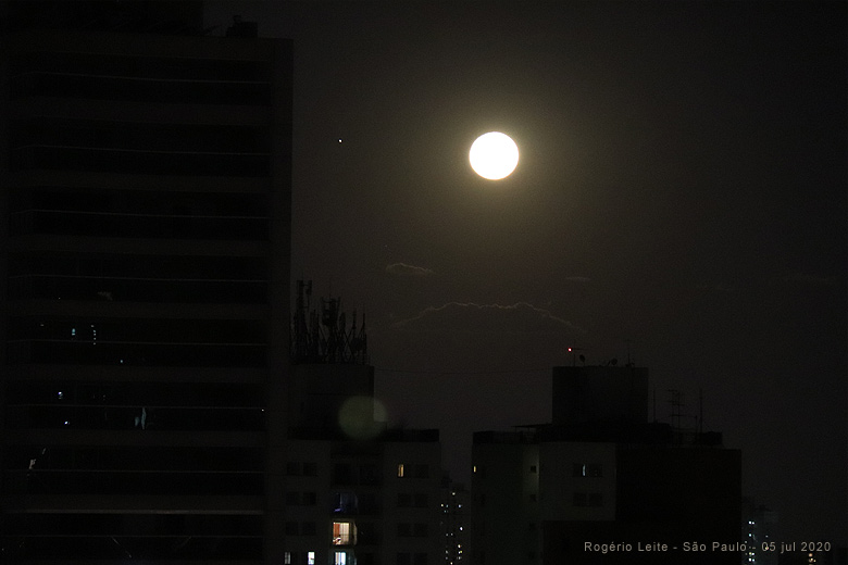 Conjuno entre Lua, Jpiter e Saturno, em 5 de julho de 2020. A foto foi feita na cidade de So Paulo, a partir do bairro de Vila Mariana. Jpiter pode ser visto  esquerda da Lua. Saturno est muito abaixo, escondido pelos prdios prximos ao horizonte.<BR>